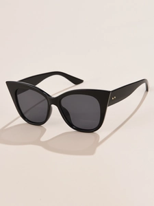 Detail of black cat-eye sunglasses with gold metal dots and artistic shadow contrast