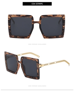 Détail de lunettes de soleil carrées écaillées avec branches en chaîne dorée et verres