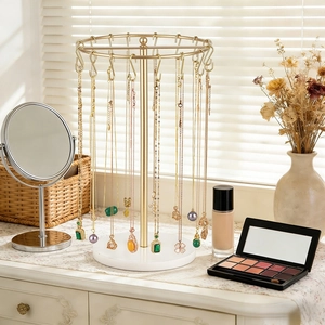 Rotating gold metal necklace stand with white marble base and elegant vanity display