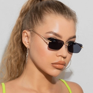 Detail shot of rimless rectangular sunglasses with gold metal arms and large hoop earrings