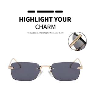 Close-up of rimless square sunglasses with dark grey lenses and gold metal diamond texture