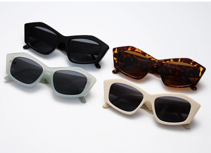 Quattro occhiali da sole geometrici oversize in nero, tartarugato e verde su sfondo bianco