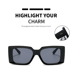 Close-up of black rectangular sunglasses featuring gold dot accents and polished frames