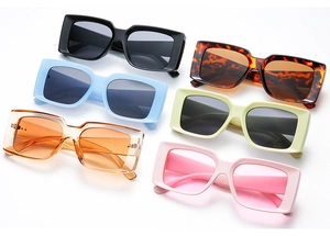 Flat lay of retro square sunglasses in various candy colors including black and tortoise