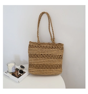 Detail view of handmade hollow-out crochet straw tote bag with floral patterns