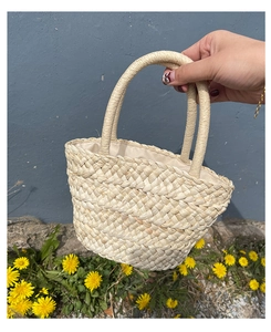 Detail of hand-woven corn husk bag with round handles and beige fabric lining