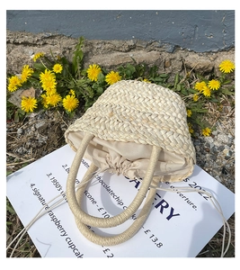 Detail of hand-woven straw bucket bag with drawstring liner on a rustic stone background