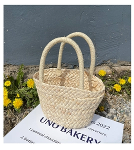 Close-up of the woven corn husk texture and sturdy handles of this handmade straw tote