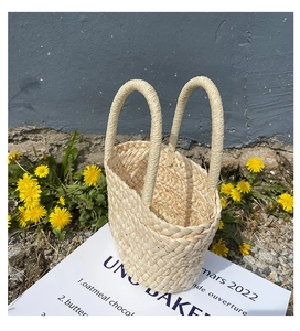 Close-up of a woven mini straw bag with circular handles on an outdoor stone path