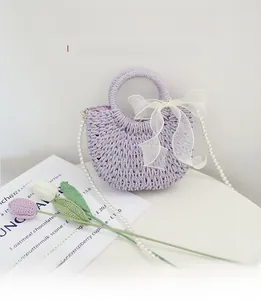 Detail of lavender straw crossbody bag with white organza bow and pearl shoulder strap