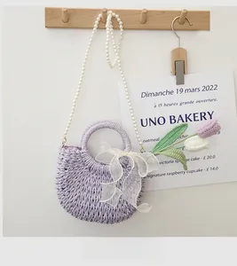 Macro detail of purple woven straw bag with translucent white bow and pearl strap