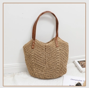 Détail du sac en paille tressée avec poignées en similicuir marron et texture zigzag