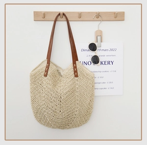 Gros plan sur le sac fourre-tout beige tissé avec des anses en cuir marron