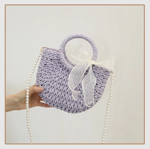 Detail of purple straw bag with large white organza bow and pearl shoulder strap