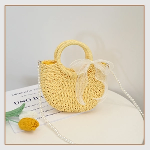 Close-up of yellow straw bag with white organza bow and pearl chain strap detail