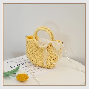 Detail of yellow straw mini bag with organza bow and imitation pearl chain strap