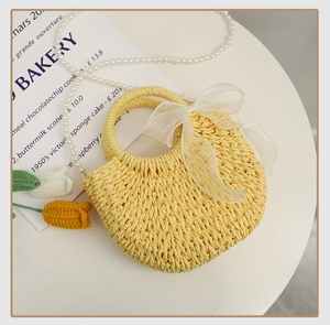 Detail of yellow straw bag featuring a white organza bow and circular handle