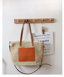 Detail of French straw tote bag featuring brown leather pocket and woven texture