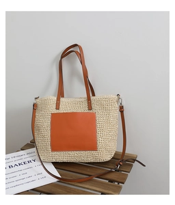 Detailed macro shot of the premium woven texture and brown leather strap on straw tote bag