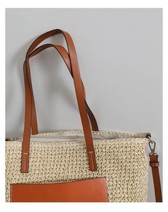 Detail of straw tote bag featuring brown leather pocket and white contrast stitching