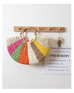 Detailed close-up of a colorful striped straw tote bag hanging on a wooden wall hook