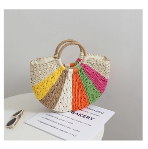 Detail of a rainbow striped straw handbag with round handles on a white tabletop