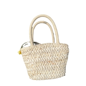 Minimalist cream woven corn husk tote bag with decorative yellow tassel for women