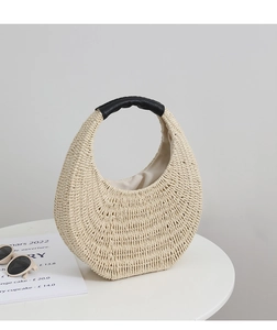Detailed texture of ivory straw hobo bag with black leather handle on white table