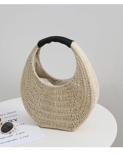 Detail of cream straw bag with black leather handle and woven crescent shape texture
