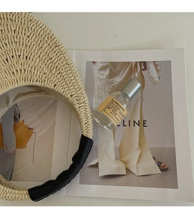 Close-up of straw woven handbag with black leather handle on a magazine background