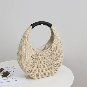Handmade cream straw woven bag with black leather handle and minimalist crescent shape