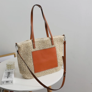 Large beige woven straw tote bag with brown leather handles for beach or travel