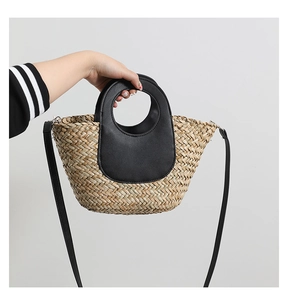Detail of hand-woven straw crossbody bag with black leather handles and circular cutout