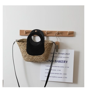Detail of handmade straw bag with black leather round handle and slim shoulder strap