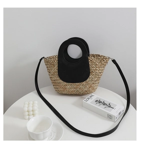 Detail of hand-woven straw bag featuring black leather handles and textured fiber