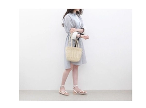 Detailed handmade straw tote bag shown with blue striped dress for a summer beach look