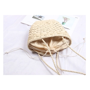 Straw woven bucket bag with drawstring liner on white fabric background, 45-degree angle view