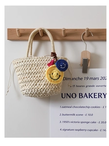 Dettaglio della borsa in paglia con ciondolo smiley in maglia giallo e nappa rosa