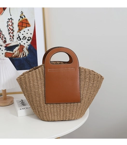 Detail of French retro straw tote bag featuring brown leather handles and stitching