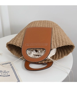 Detail of hand-woven straw tote with brown leather handles and drawstring cotton lining