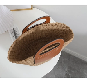 Detailed top view of handmade straw tote featuring brown leather handles and woven texture