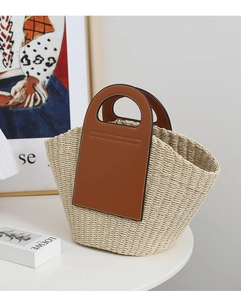 Detail of raffia woven tote featuring brown leather trim and white contrast stitching