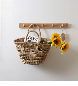 Detail of hollow-out mesh straw handbag with double woven handles hanging on a wall hook