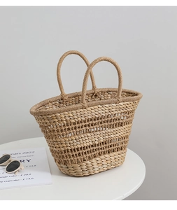 Detail shot of a French vintage hollow straw handbag with dual handles on a white table