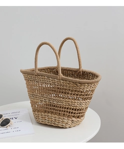 Detailed close-up of handmade hollow straw woven bag with circular handles for beach vacation