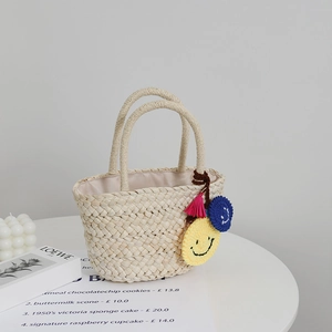 Graziosa borsa in paglia per bambini con ciondolo a faccina gialla e nappa rosa