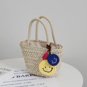 Simpatica borsa in paglia intrecciata con ciondoli a forma di sorriso e nappa rosa