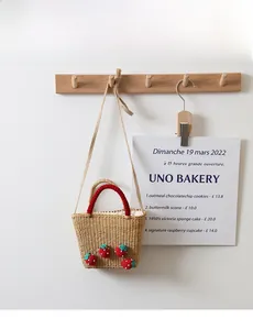 Détail d'un sac en paille tissé avec fraises au crochet et poignées rouges sur crochet