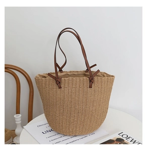 Detail of hand-woven straw bucket bag featuring premium brown leather handle and texture