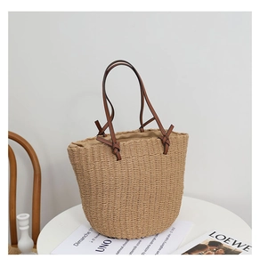 Detail of handmade straw bucket bag with brown leather handles and fabric lining
